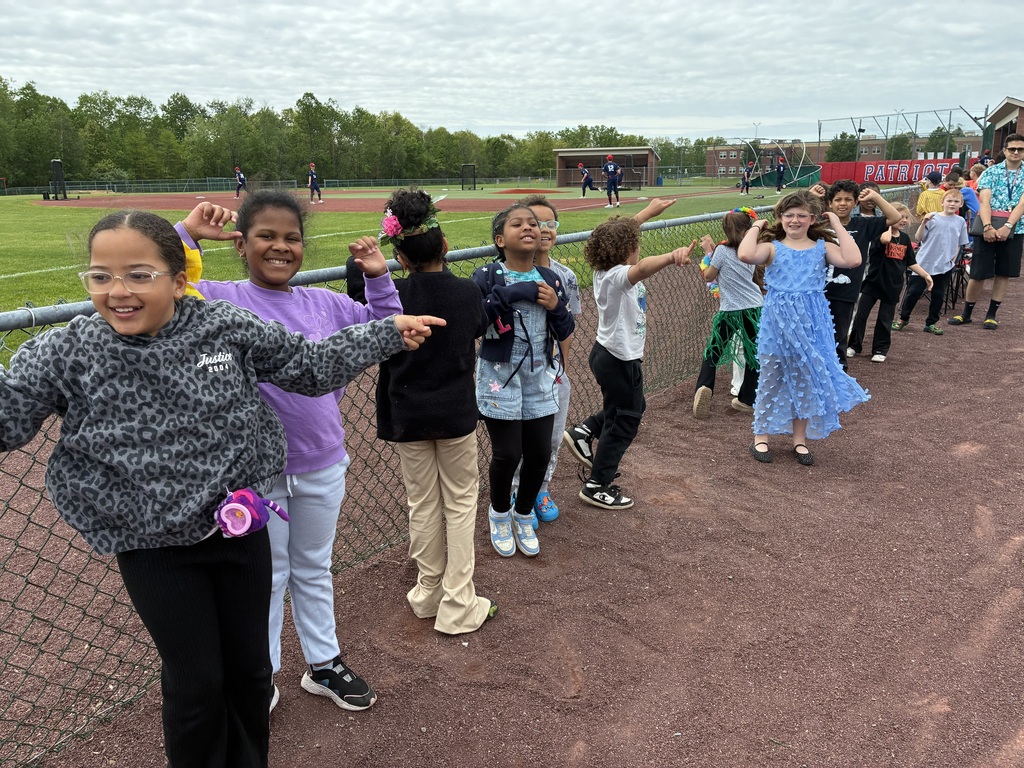 Primary students and varsity baseball players outside the baseball field 