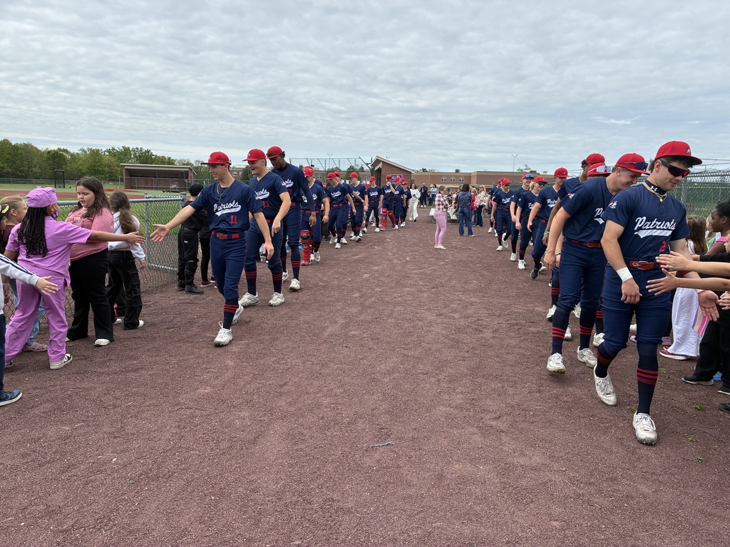 Primary students and varsity baseball players outside the baseball field 