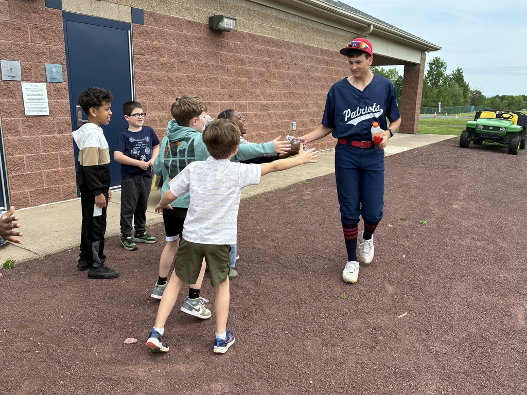 Primary students and varsity baseball players outside the baseball field 