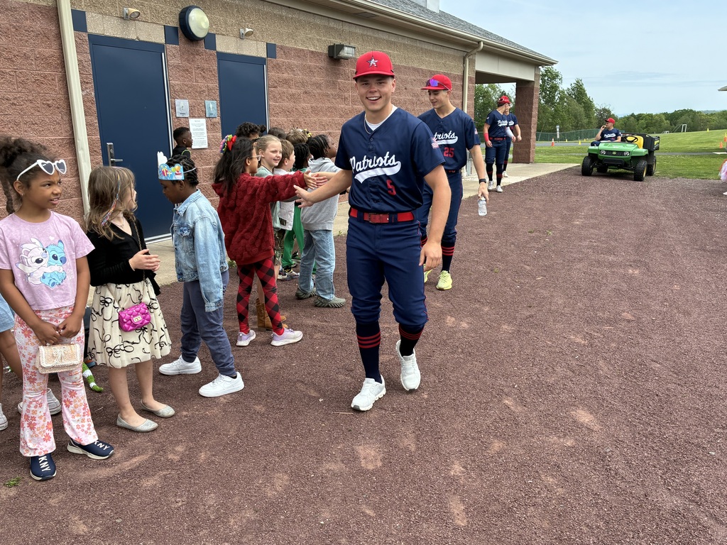 Primary students and varsity baseball players outside the baseball field 