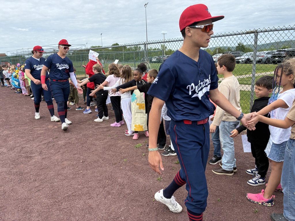 Primary students and varsity baseball players outside the baseball field 
