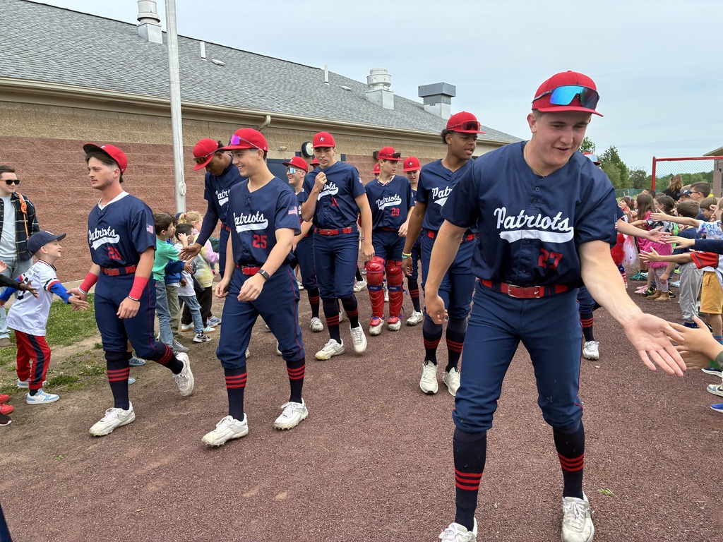 Primary students and varsity baseball players outside the baseball field 