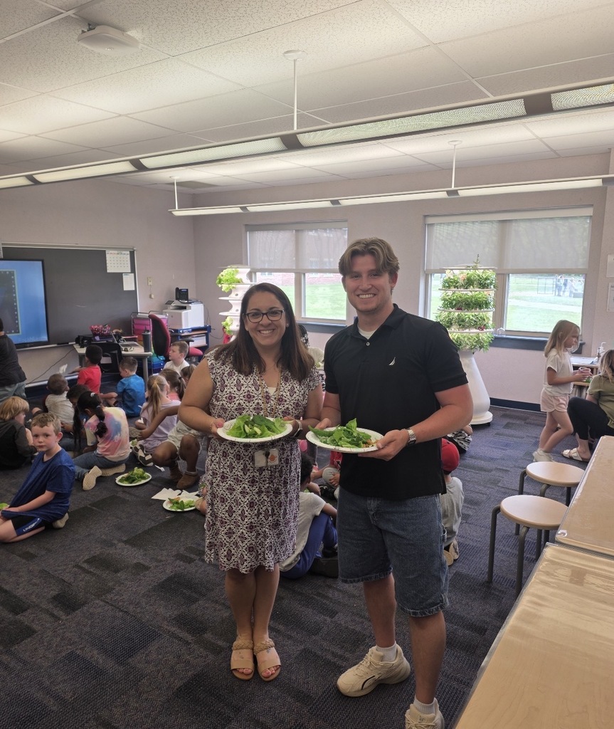 Students and teachers in the stem lab with hydroponic farm stands with lettuce and  flowers 