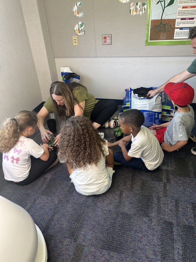 Students and teachers in the stem lab with hydroponic farm stands with lettuce and  flowers 