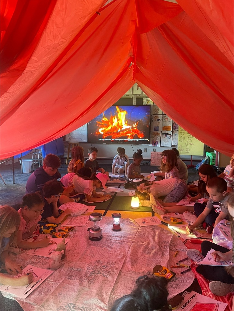 Students under a giant red tent in their classroom. 