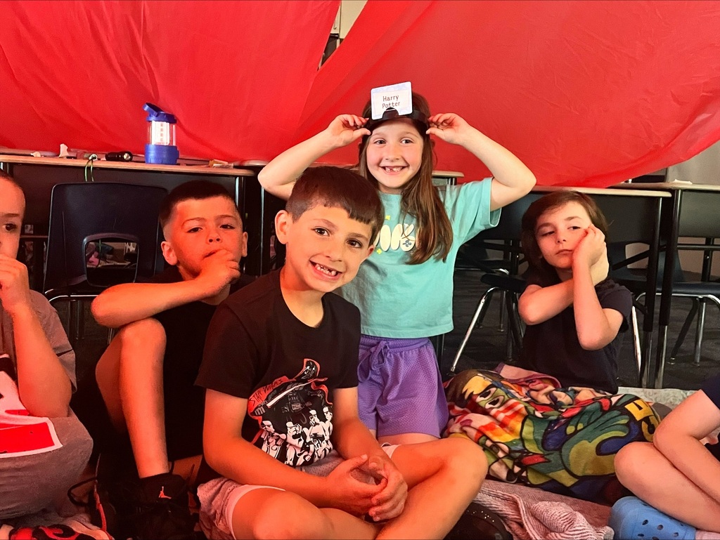 Students under a giant red tent in their classroom. 