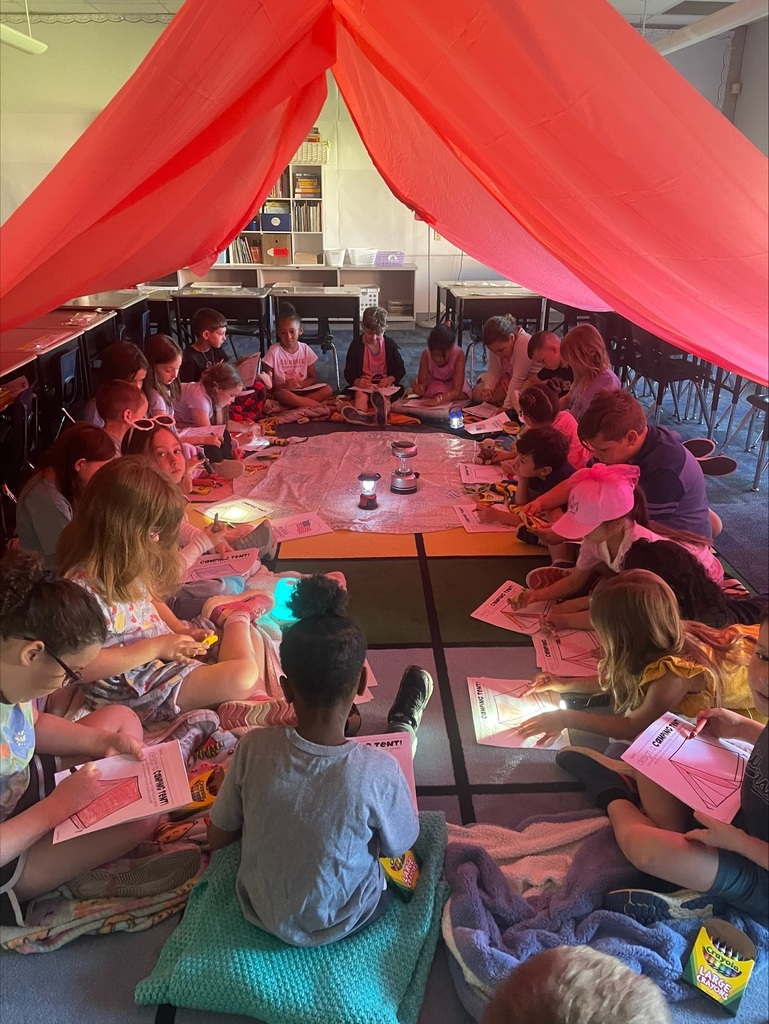 Students under a giant red tent in their classroom. 