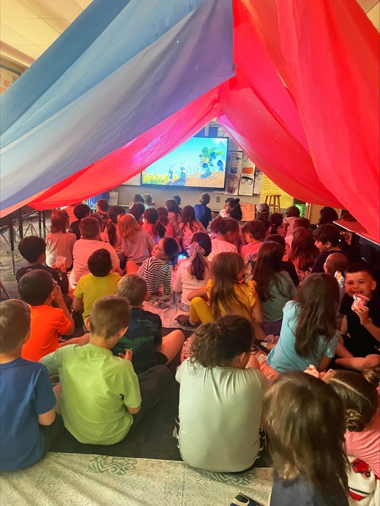 Students under a giant red tent in their classroom. 