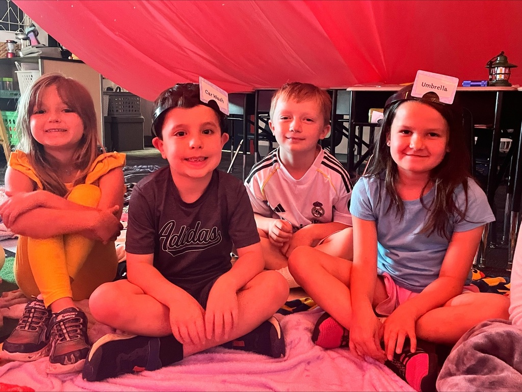 Students under a giant red tent in their classroom. 