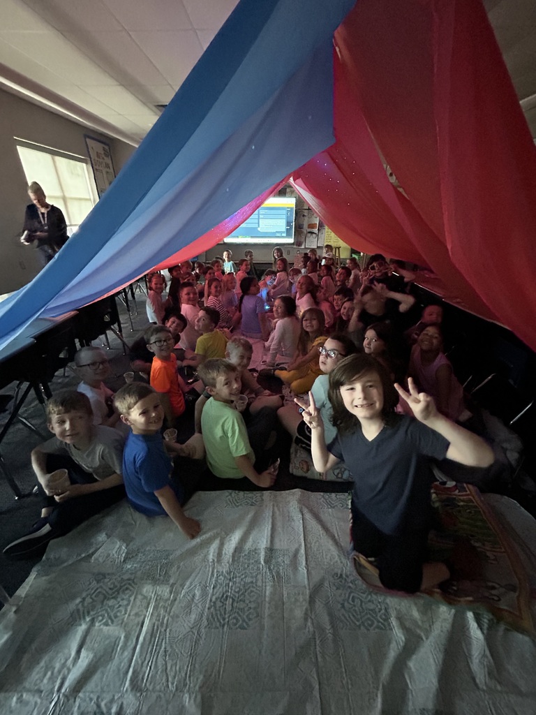 Students under a giant red tent in their classroom. 