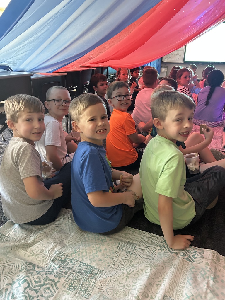 Students under a giant red tent in their classroom. 
