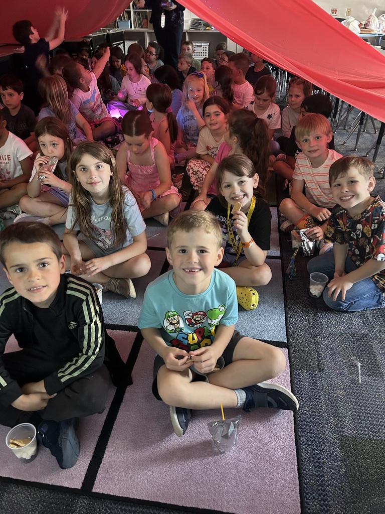 Students under a giant red tent in their classroom. 