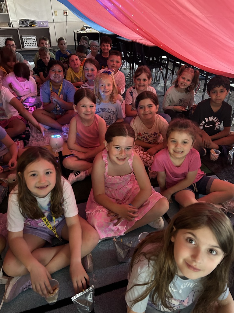 Students under a giant red tent in their classroom. 