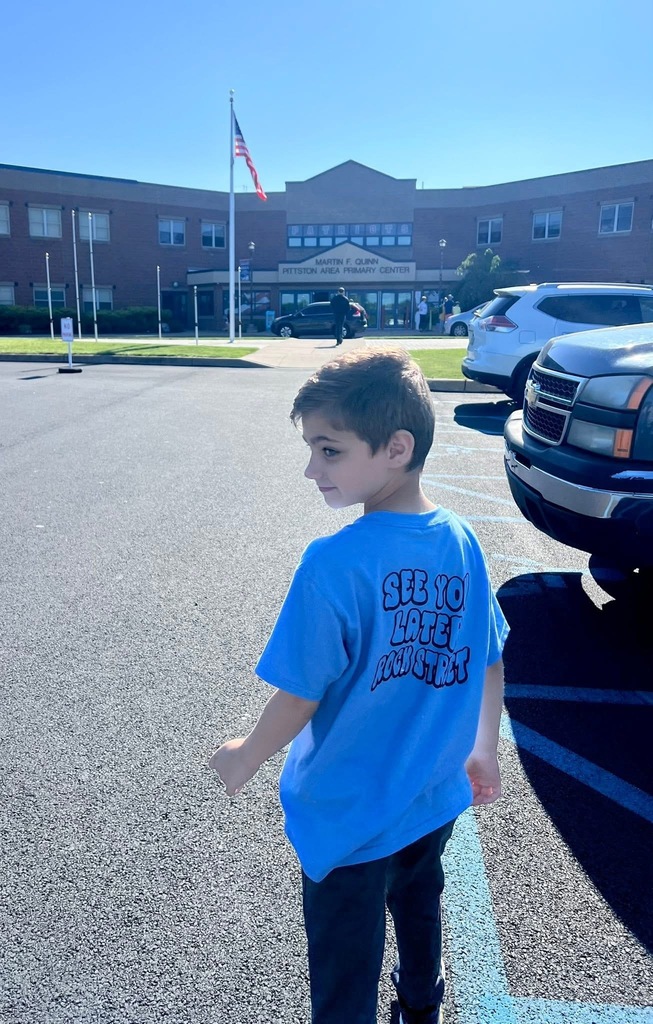 A student wear an peace out rock street shirt in front of the school