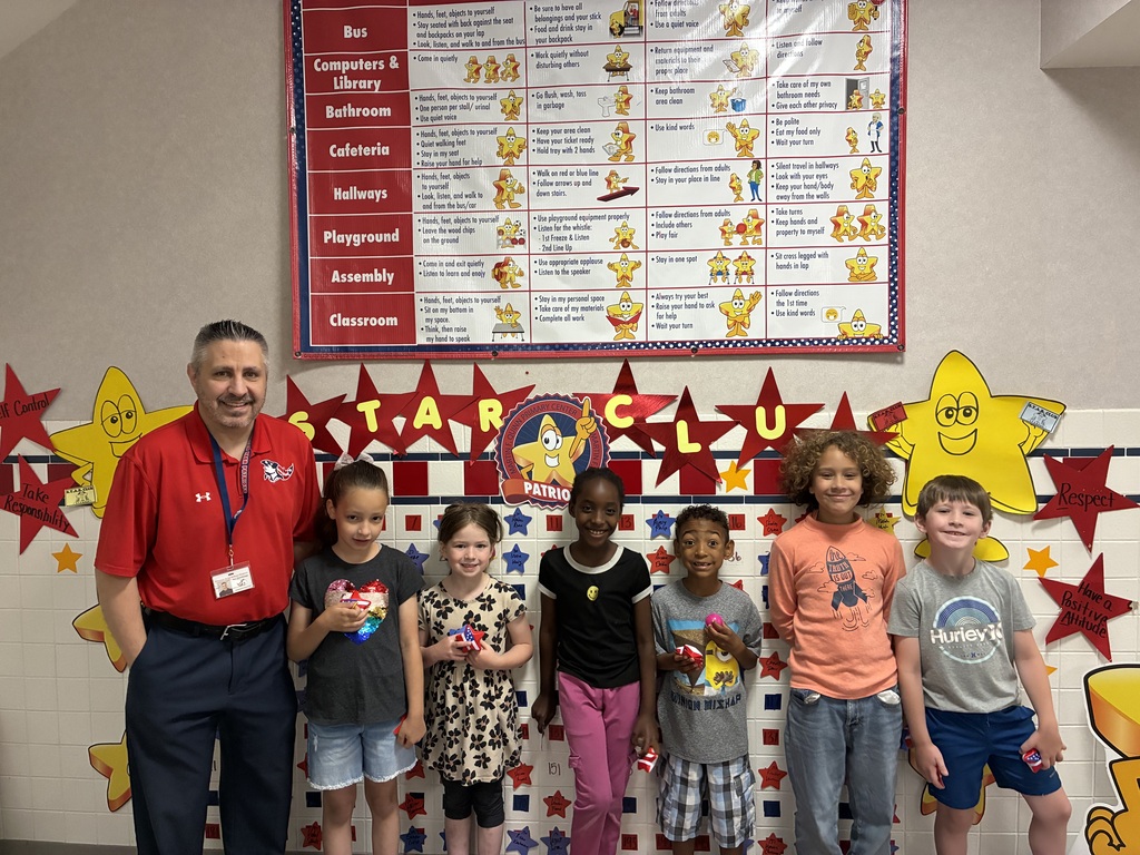 Mr savokinas and students smiling together in front of the star board. 
