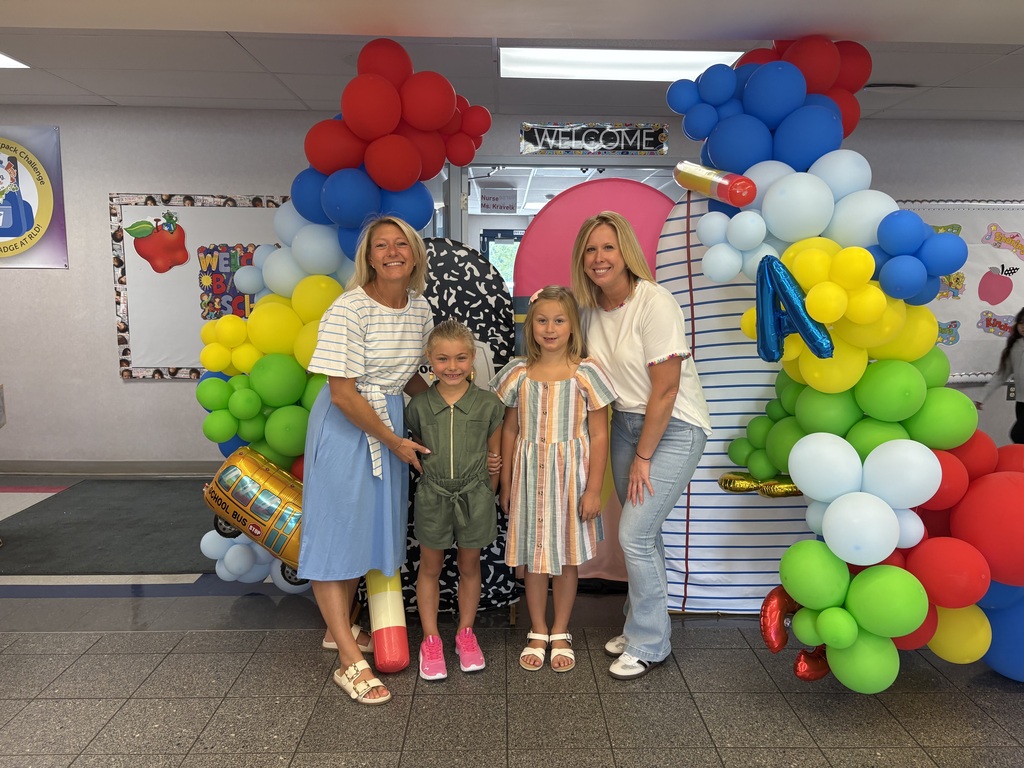 Teachers and kids infront of a ballon backdrop in the school lobby!