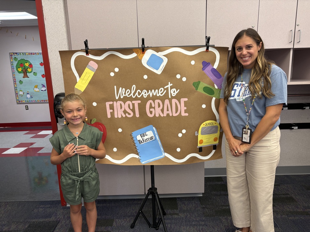 A student and teacher in front of a painted banner.