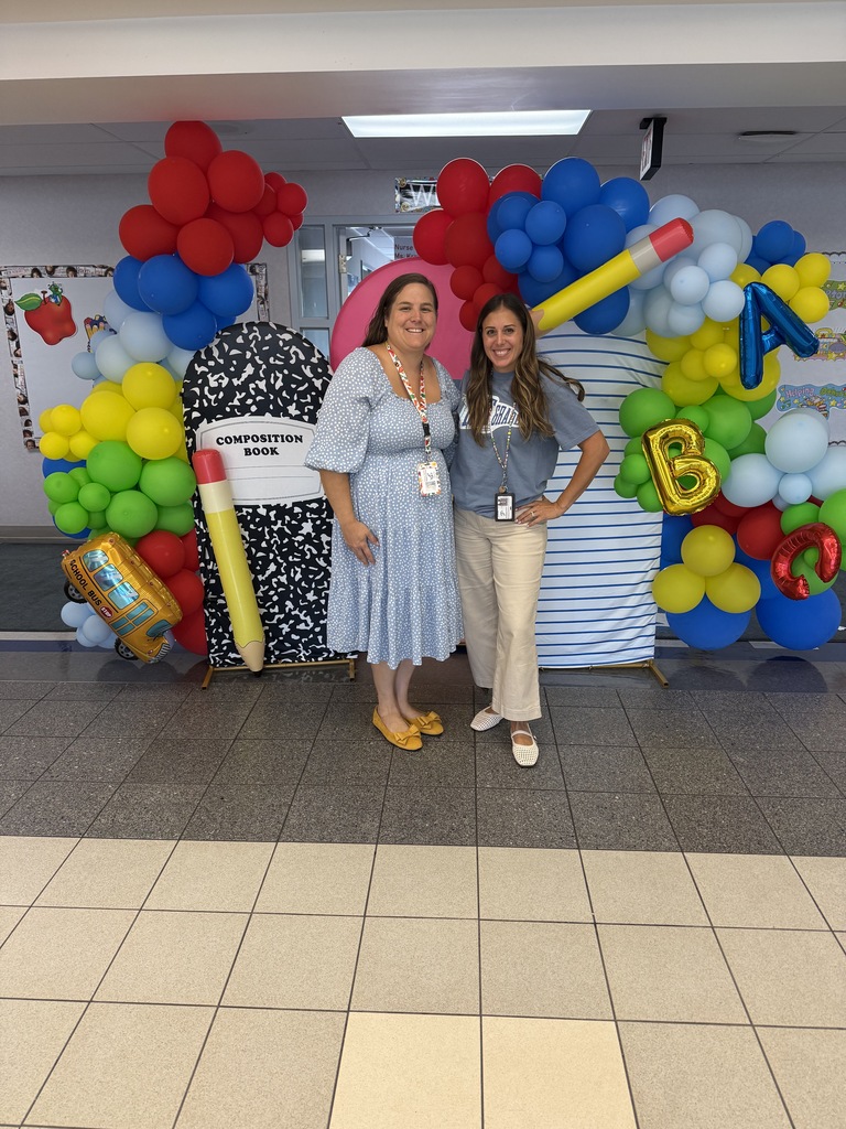 Teachers infront of a ballon backdrop in the school lobby!