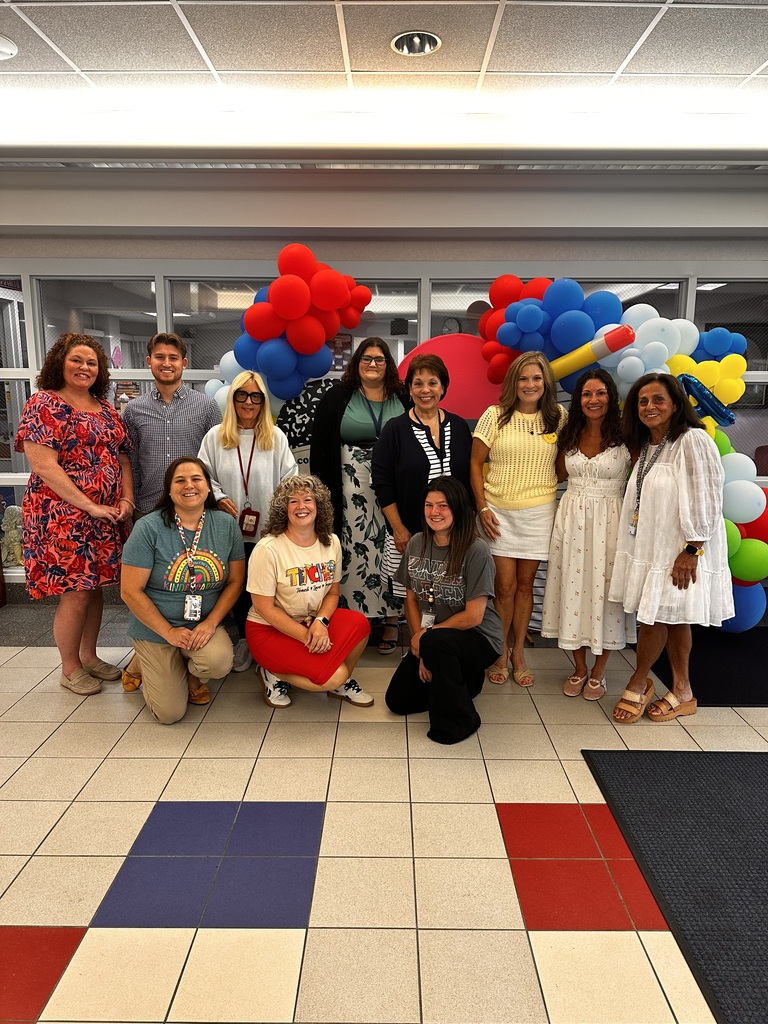A group of teachers in front of balloons,