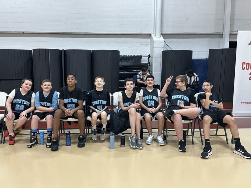 group of Special Olympic basketball players sit in chairs in gymnasium