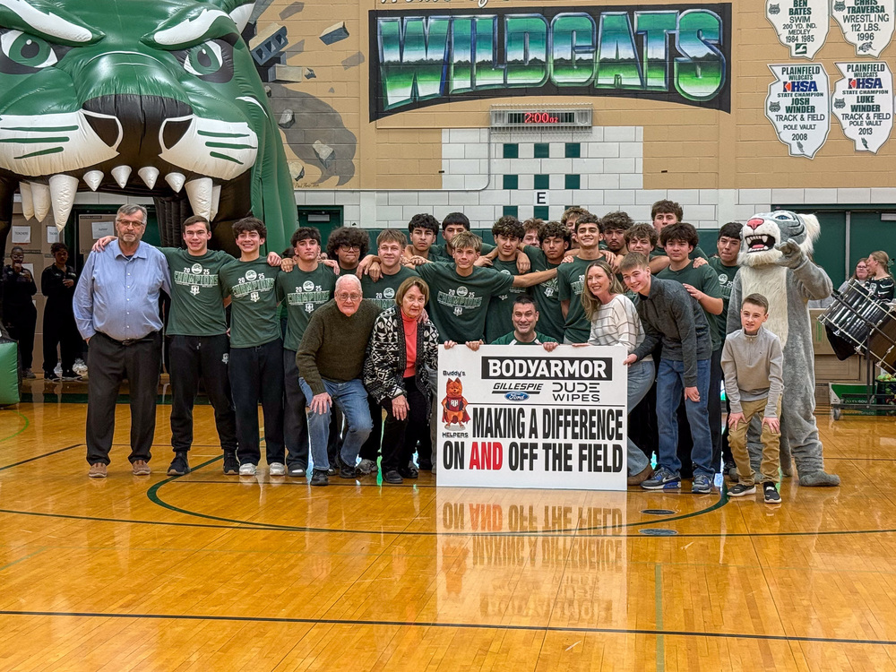 Group of people standing in gymnasium in front of sign