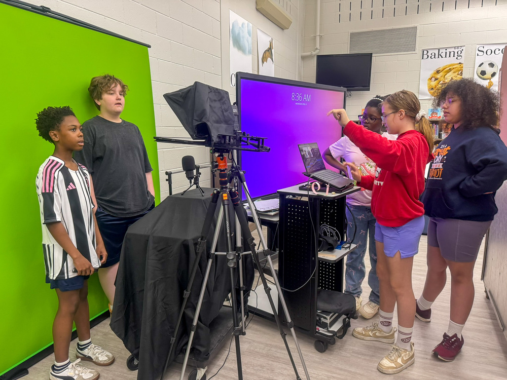 group of students in front of and behind a camera do morning announcements