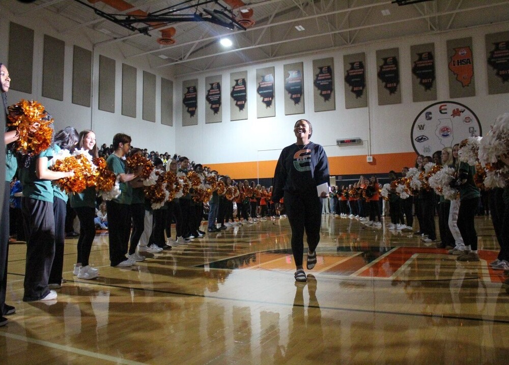 PEHS junior Taylor Miller walking in gym surrounded by her peers cheering for her