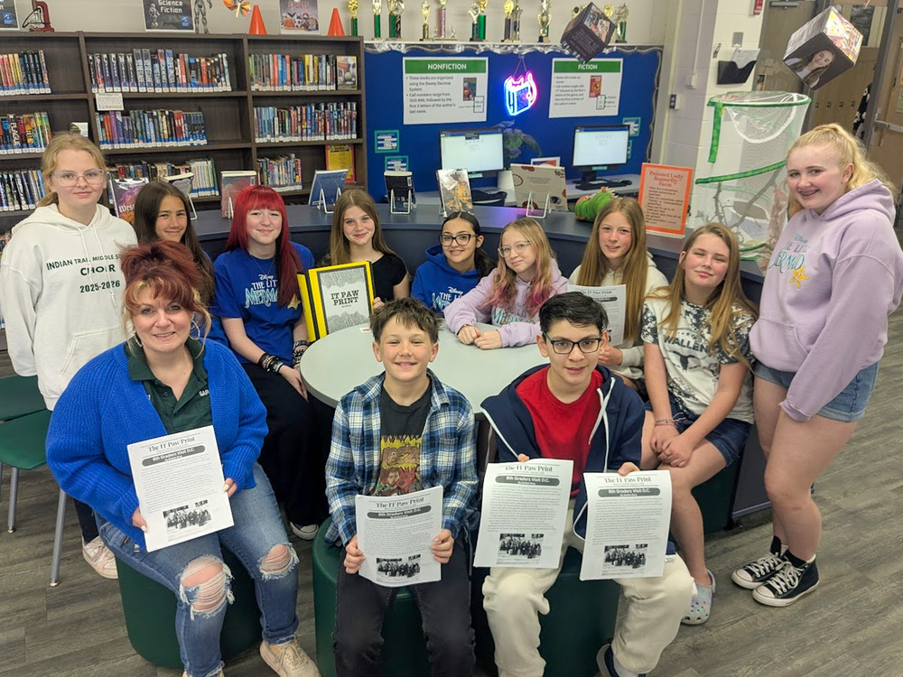 group of students, on adult hold up copies of Paw Print newspaper