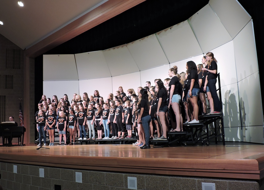 group of middle school student singers stand on risers