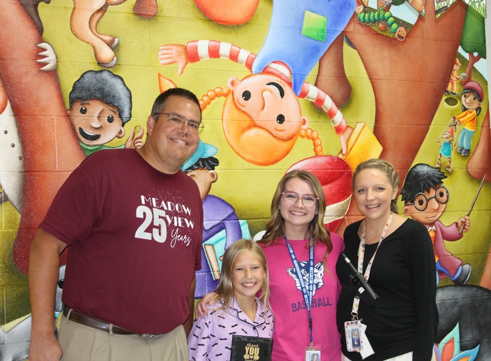 Four people stand in front of colorful mural