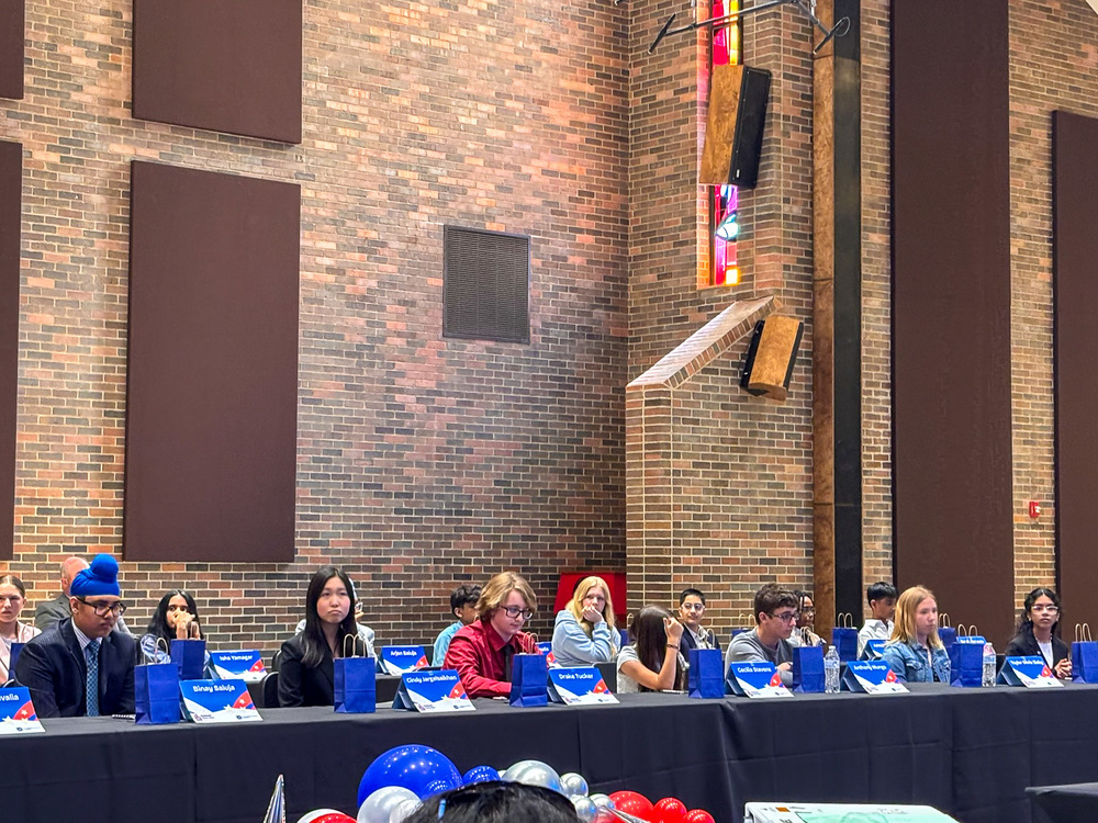 group of students sitting at tables in auditorium