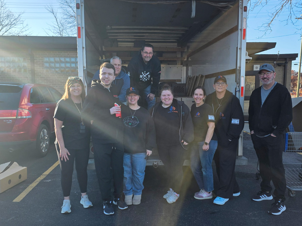 group of adults standing in front of open box truck