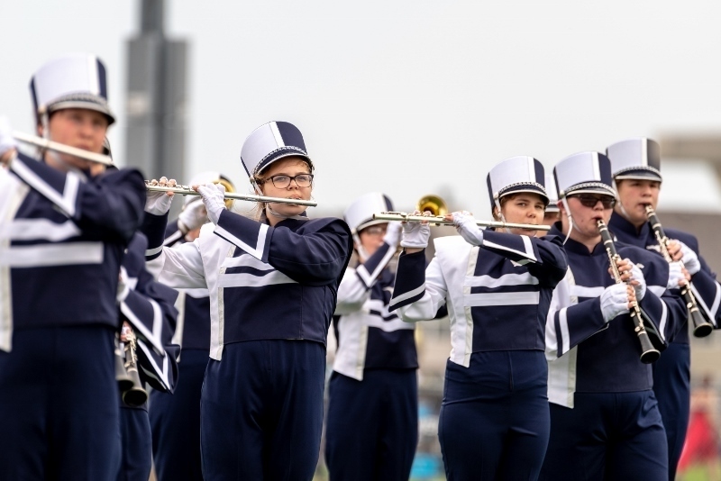 blue and white uniformed band students playing instruments