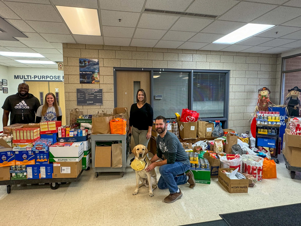 four people and one dog stand amid food donations