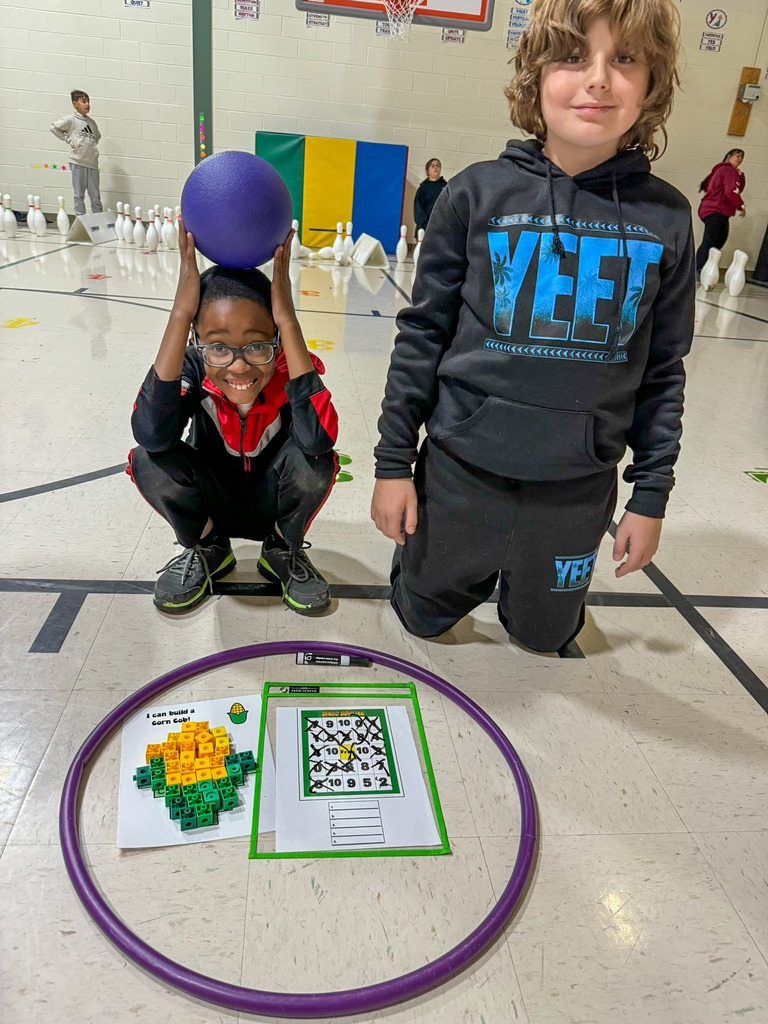 two students gathered around a hula hoop with paper inside it