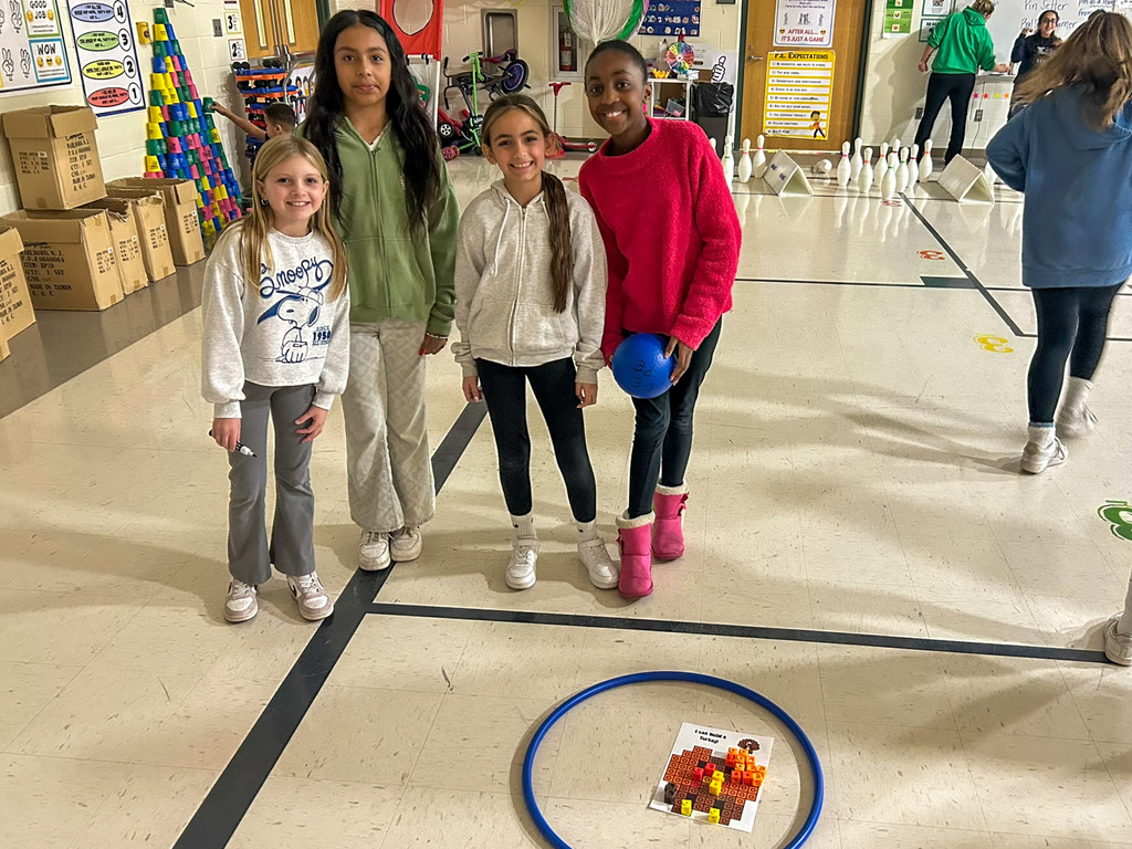 four students gathered around a hula hoop with paper inside it