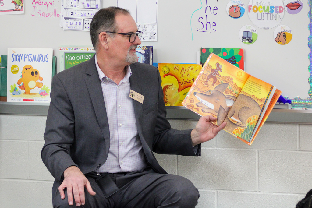 man reads book to students in classroom