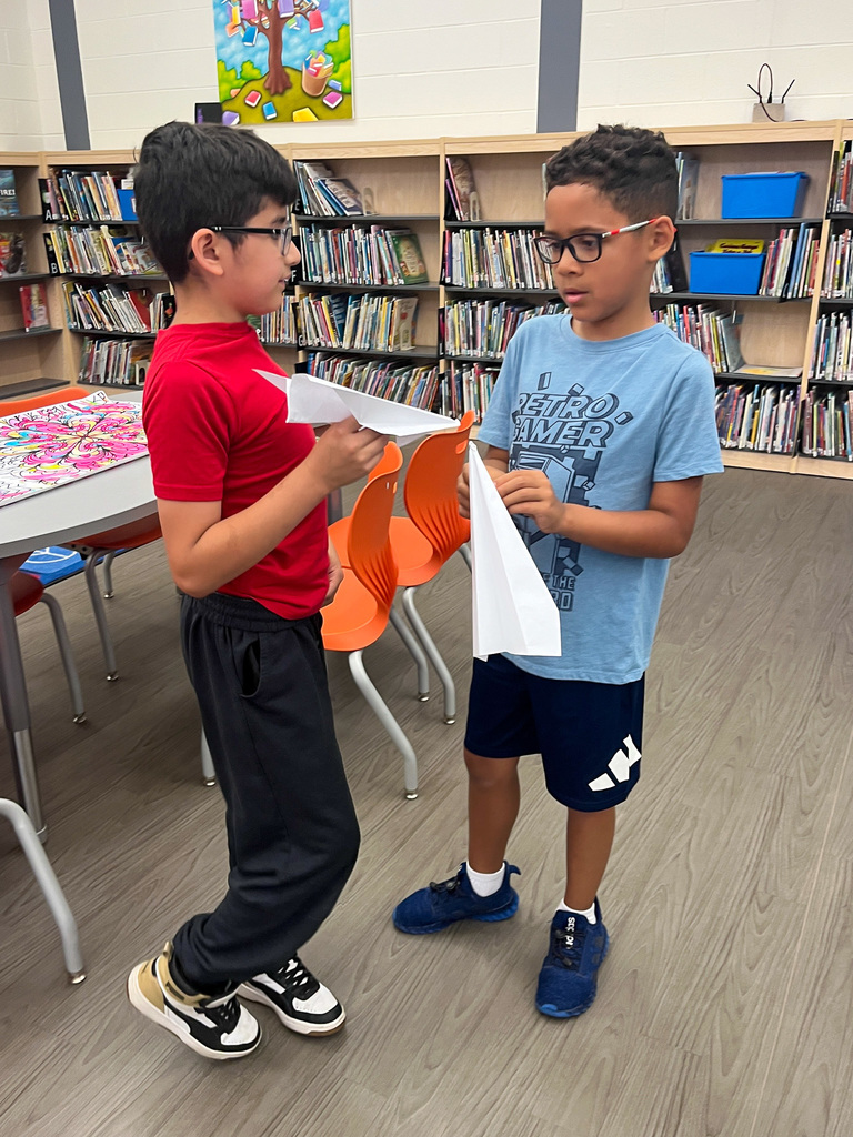 two students hold paper airplanes