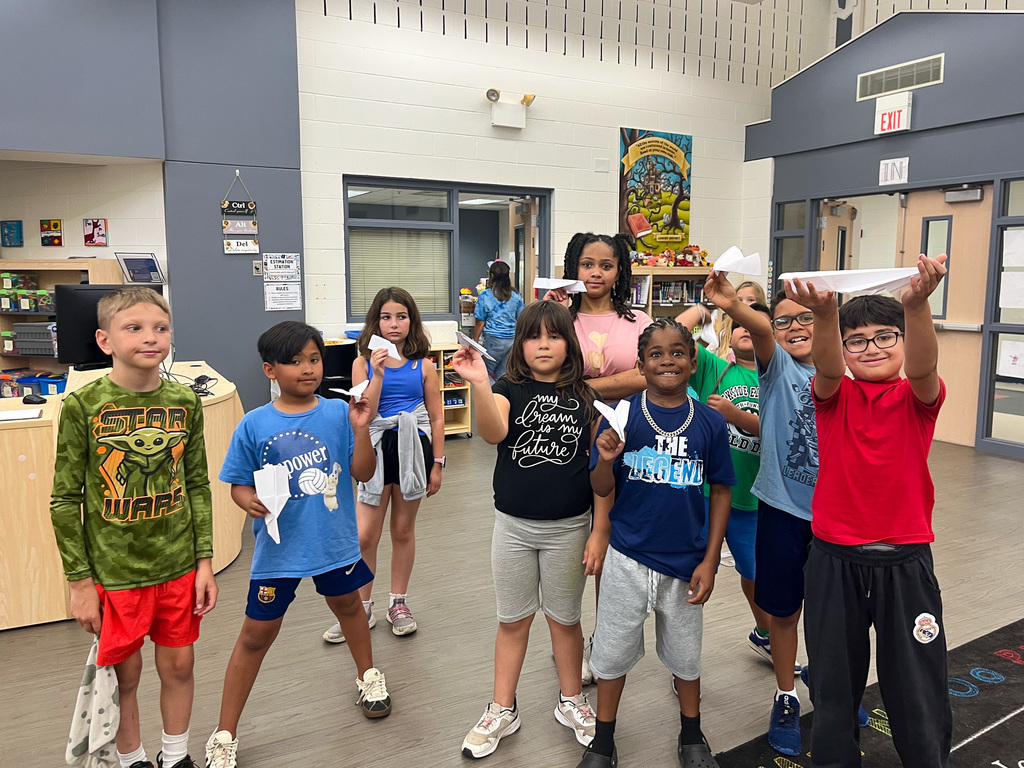 group of elementary school students hold up their paper airplanes