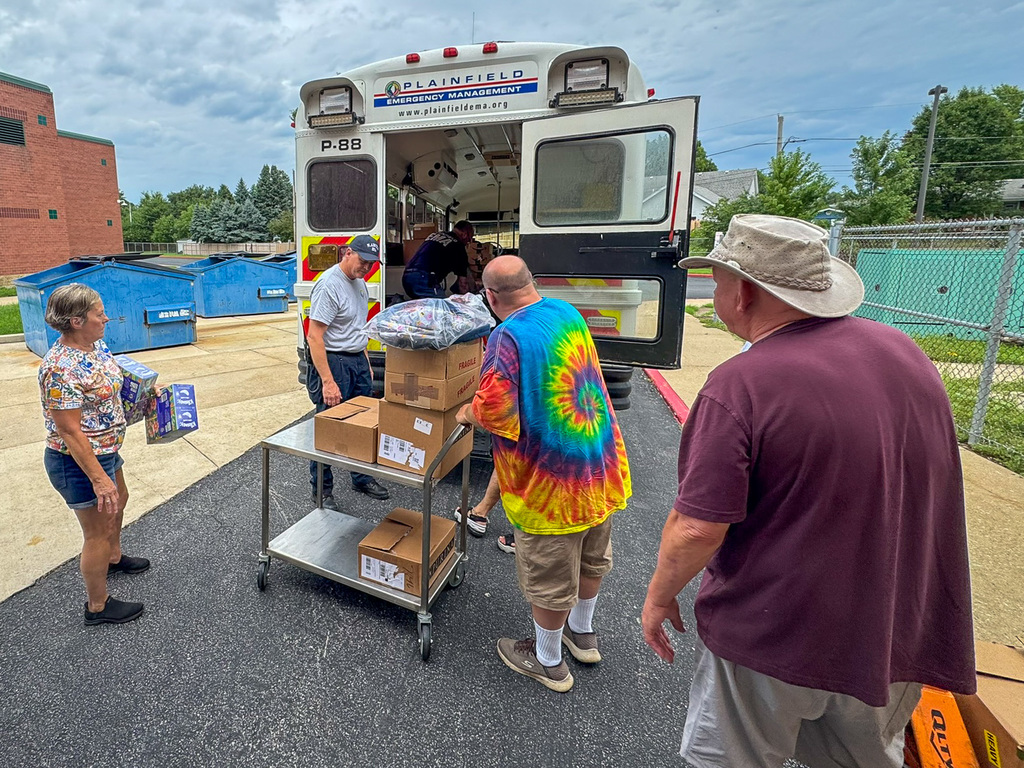 several adults unload school supplies from a small bus