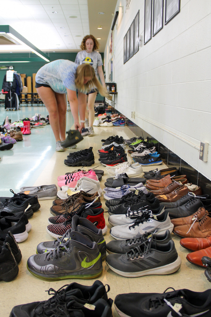 Two students organize shoes in floor