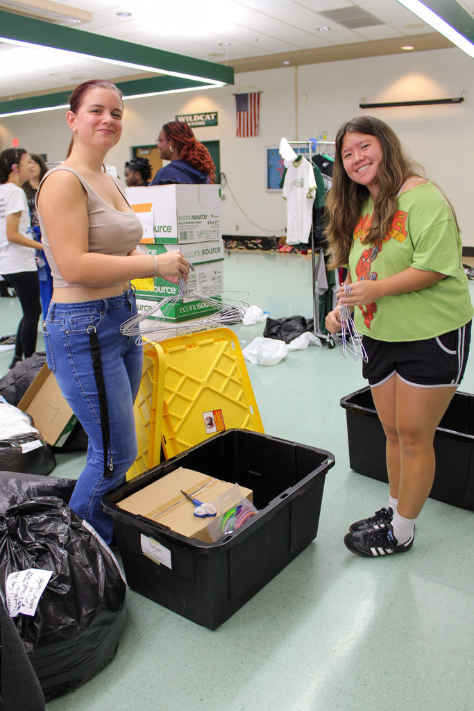 two high school students organize clothing hangers