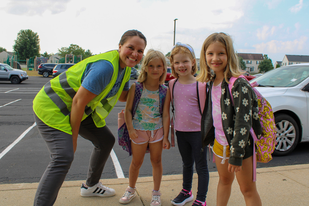 woman wearing yellow safety vest poses with three students