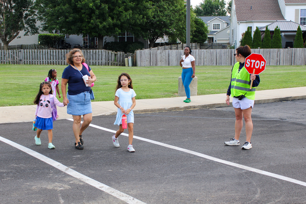 family walks across crosswalk to school