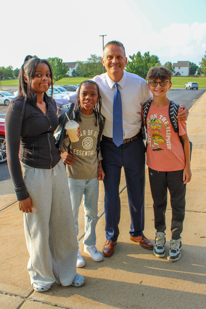 principal poses with three students before school
