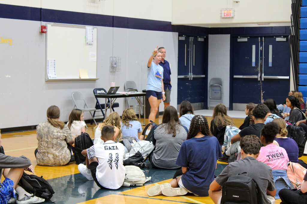 teacher holds up hand in front of students in gym