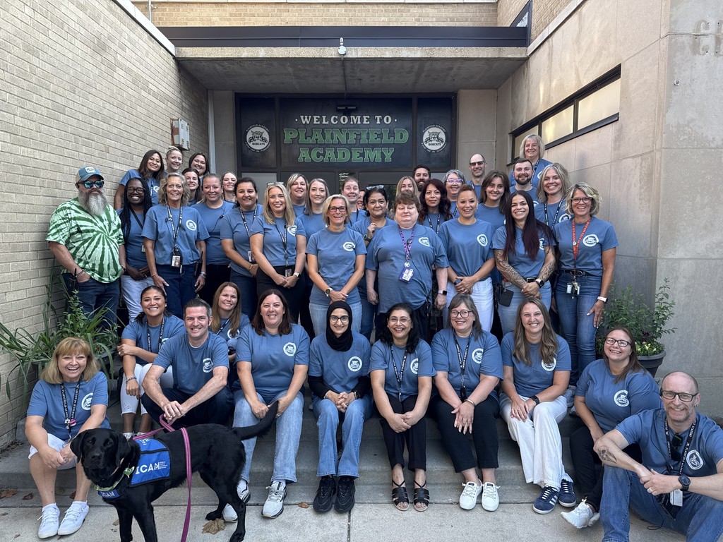 staff pose in front of school
