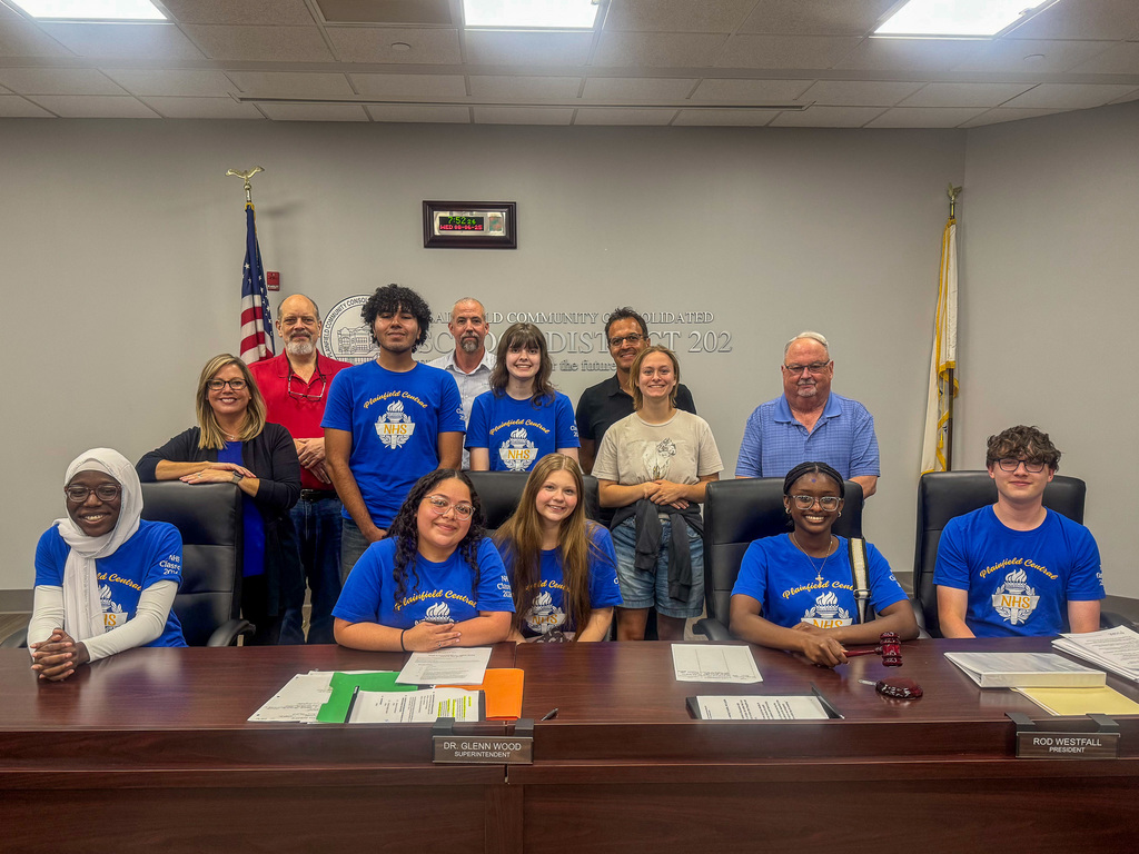 group of National honor society high school students sit and stand with board of education members