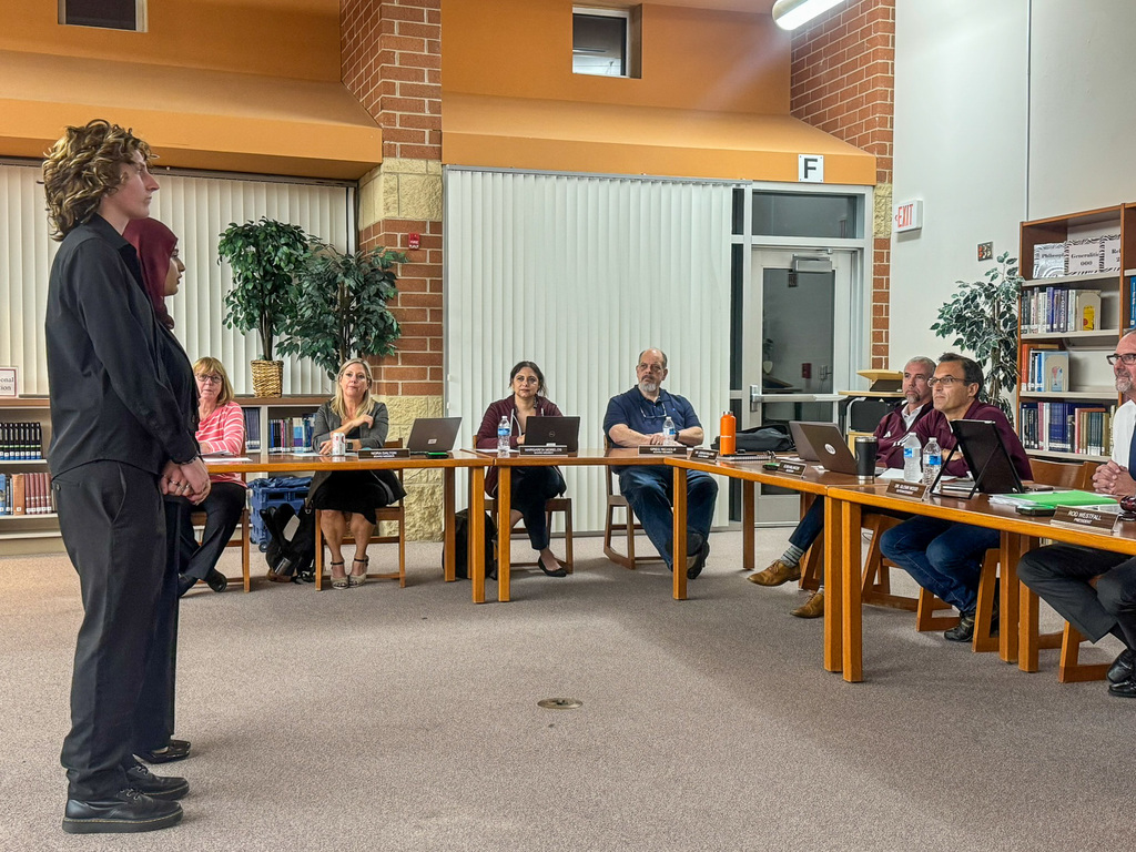 Two students stand and speak in front of the school board