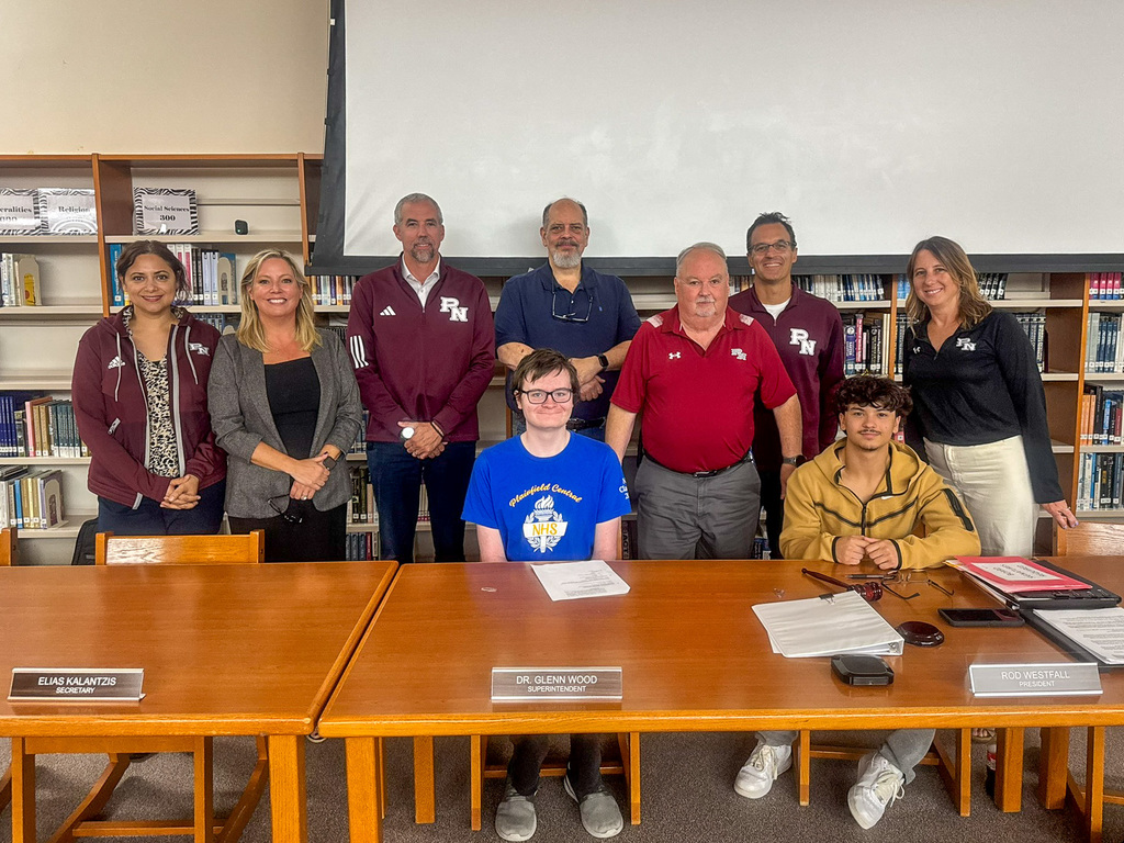 Board of Education poses at table with two Plainfield High School Central Campus students